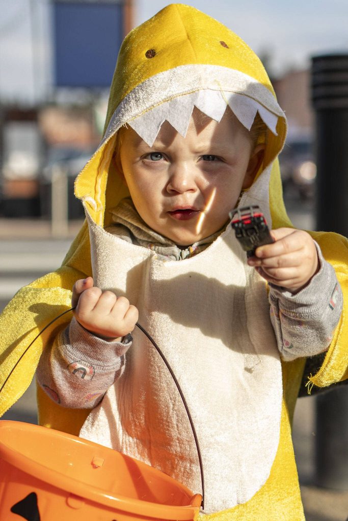 Nova Eckaus, 2, poses for a photo during the Downtown Trick or Treat event in Monroe, Washington on Tuesday, Oct. 31, 2023. Children, teens and families walked Main Street to collect candy from local businesses. Dogs sported costumes as well and decorations adorned buildings. (Annie Barker / The Herald)