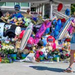 A memorial for Bothell Police Officer Jonathan Shoop, killed in the line of duty on Monday evening, grows on top of and around a Bothell Police Car parked at Bothell City Hall on Wednesday, July 15, 2020, in Bothell, Wash. (Mike Siegel/The Seattle Times via AP)