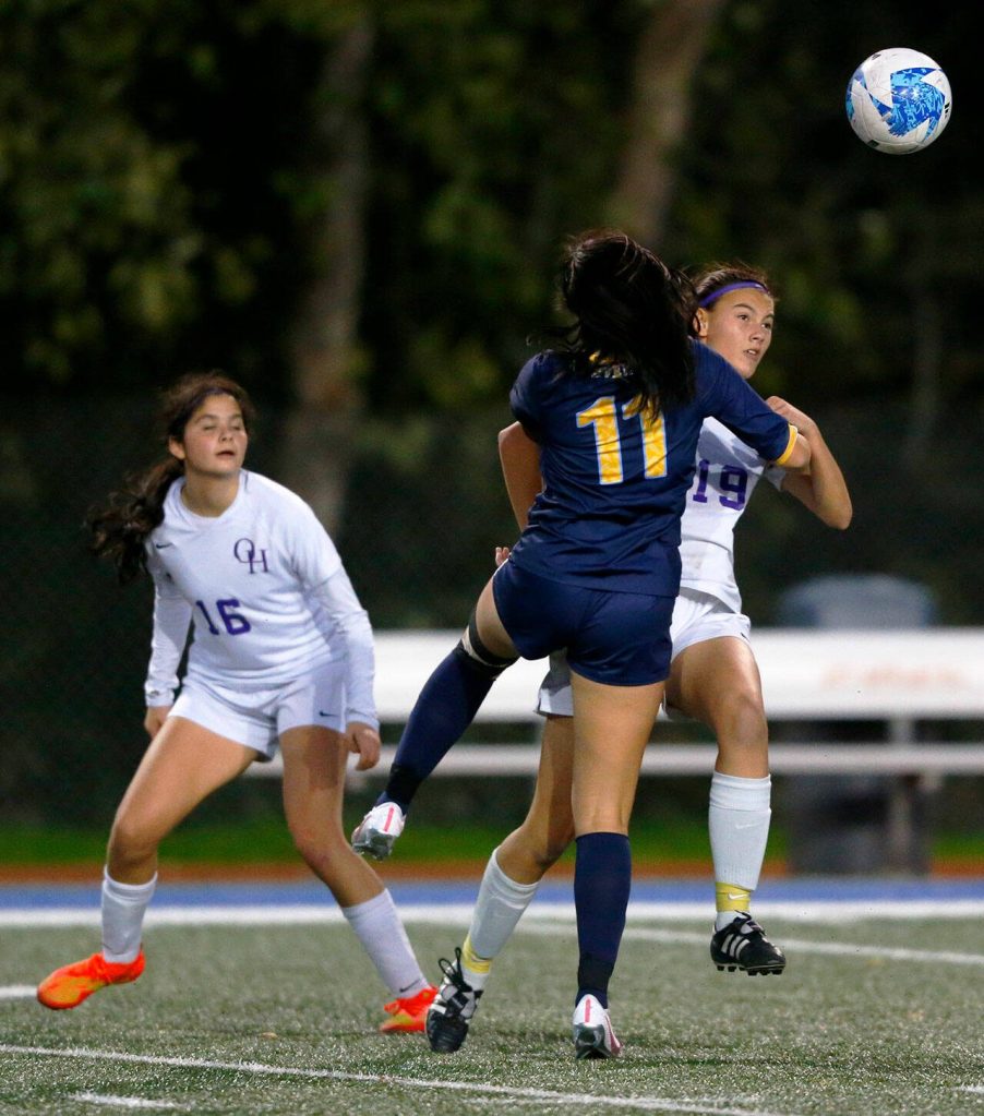 Everett defender Bella Nguon collides with another player while heading the ball away during a district playoff matchup against Oak Harbor on Thursday, Nov. 2, 2023, at Shoreline Stadium in Shoreline, Washington. (Ryan Berry / The Herald)