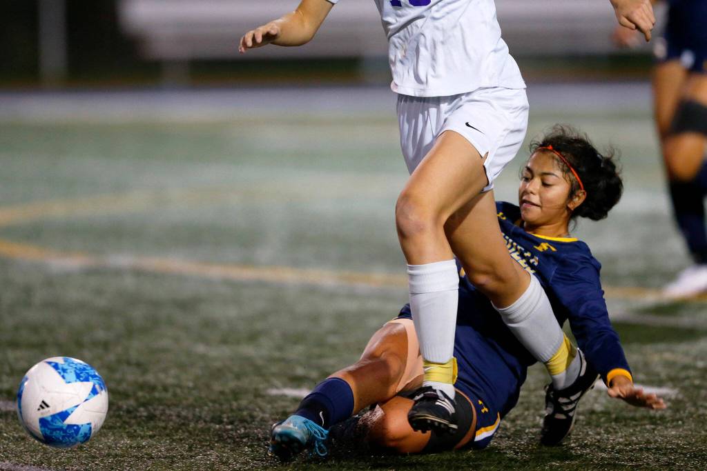 Everett midfielder Genesis Molina Escobar tackles the ball away from an opponent during a district playoff matchup against Oak Harbor on Thursday, Nov. 2, 2023, at Shoreline Stadium in Shoreline, Washington. (Ryan Berry / The Herald)