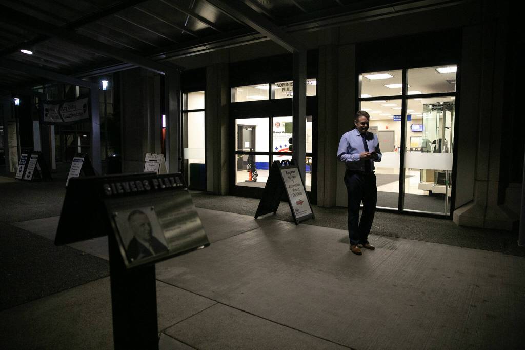 Garth Fell, incumbent Snohomish County Auditor, steps outside and away from his work in the elections office to text family about the initial results of his race to continue as auditor on Tuesday, Nov. 7, 2023, in downtown Everett, Washington. (Ryan Berry / The Herald)