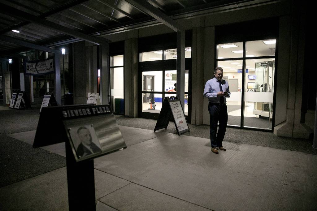 Garth Fell, incumbent Snohomish County Auditor, steps outside and away from his work in the elections office to text family about the initial results of his race to continue as auditor on Tuesday, Nov. 7, 2023, in downtown Everett, Washington. (Ryan Berry / The Herald)