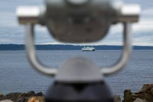 A Washington State Ferry is seen approaching Edmonds from beyond a telescope at Brackett’s Landing on Tuesday, Sept. 12, 2023, in Edmonds, Washington. (Ryan Berry / The Herald)