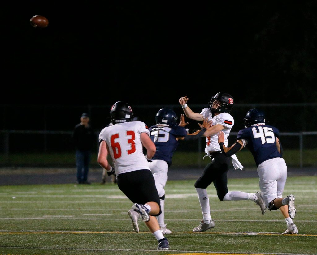 Ballard quarterback Joe Farley throws under pressure, resulting in an Arlington interception during a playoff matchup Friday, Nov. 3, 2023, at Arlington High School in Arlington, Washington. (Ryan Berry / The Herald)
