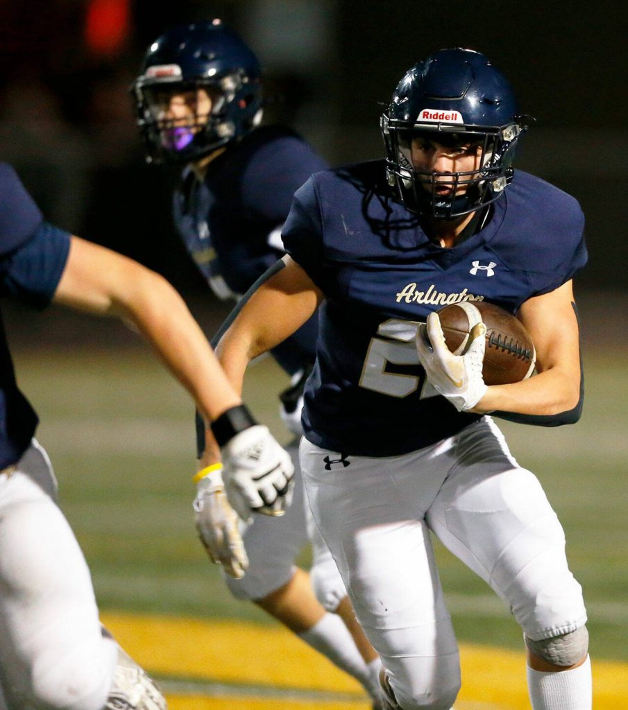 Arlington running back Caleb Reed takes a handoff against Ballard during a playoff matchup Friday, Nov. 3, 2023, at Arlington High School in Arlington, Washington. (Ryan Berry / The Herald)