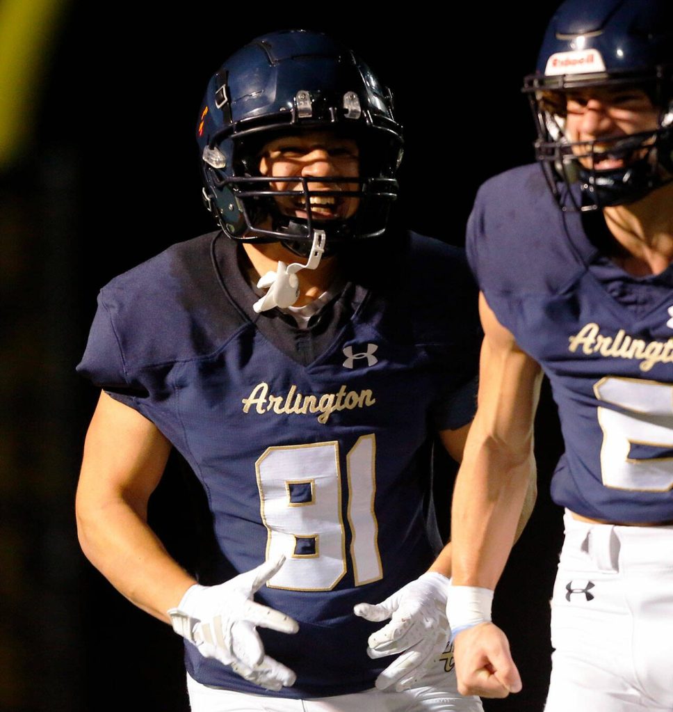 Arlington senior Stevie Balderas smiles on his way back to the sideline after a first half touchdown reception against Ballard during a playoff matchup Friday, Nov. 3, 2023, at Arlington High School in Arlington, Washington. (Ryan Berry / The Herald)