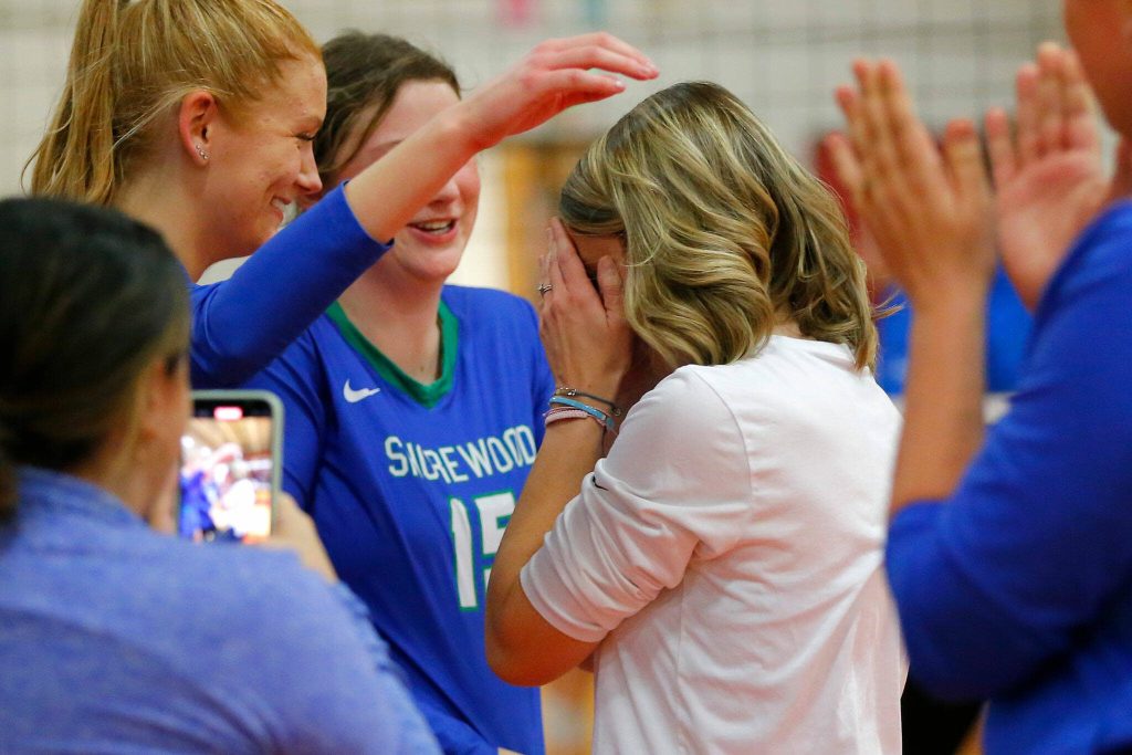Shorewood head coach Brittney Hunter covers her face as her team surrounds her after claiming victory during a Wesco 3A District volleyball matchup against Meadowdale on Thursday, Nov. 9, 2023, at Marysville Pilchuck High School in Marysville, Washington. (Ryan Berry / The Herald)