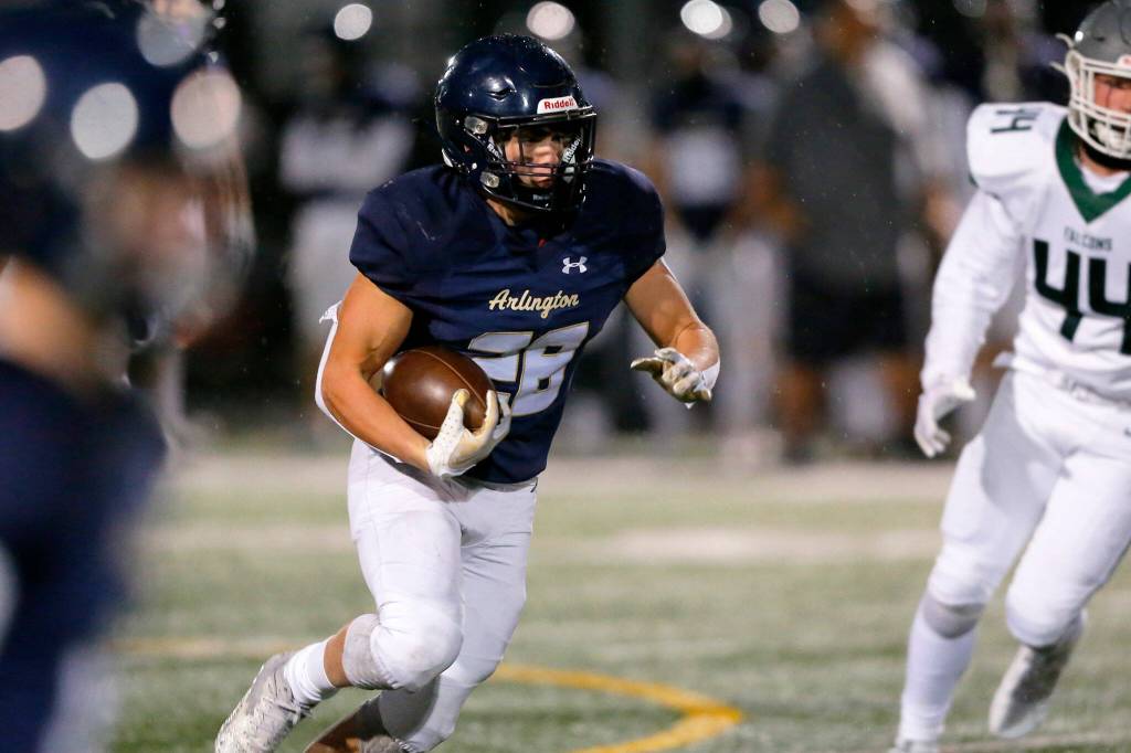 Arlingtons Caleb Reed takes a handoff and looks for space against Ridgeline during a playoff matchup Friday, Nov. 10, 2023, at Arlington High School in Arlington, Washington. (Ryan Berry / The Herald)