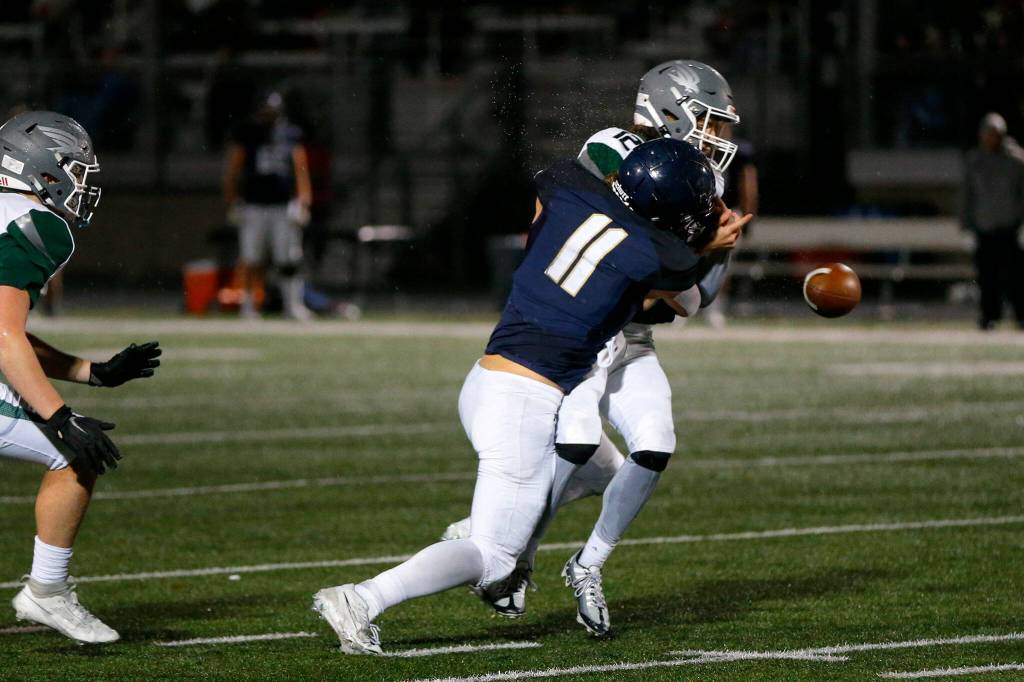 Arlington senior lineman Jeremy Fleming sacks Ridgelines Landon Garner and forces a fumble during a playoff matchup Friday, Nov. 10, 2023, at Arlington High School in Arlington, Washington. (Ryan Berry / The Herald)