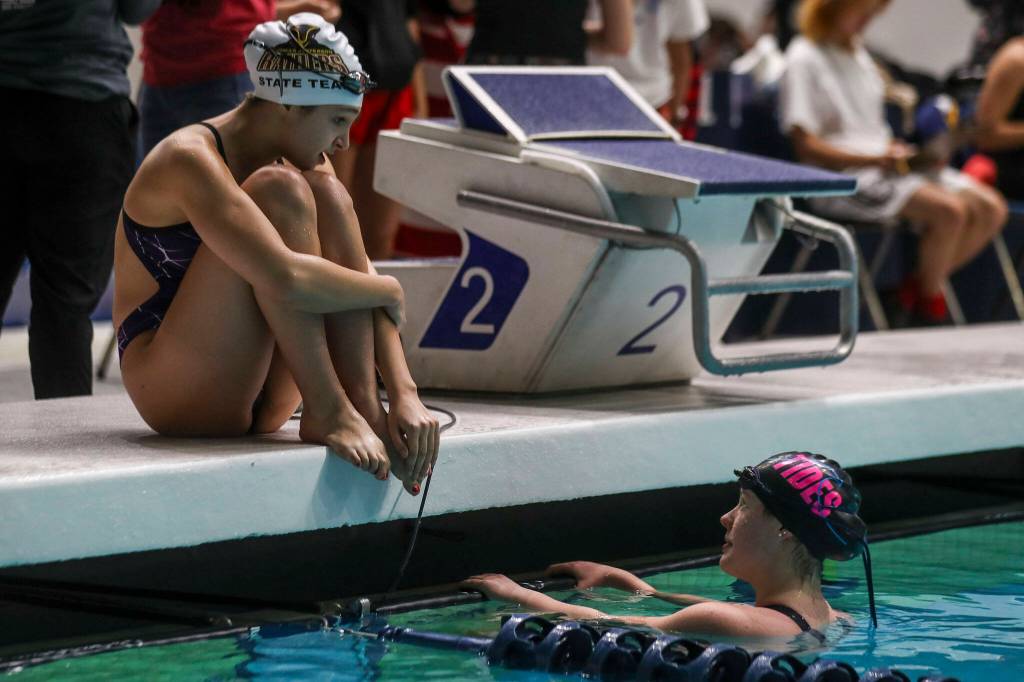 Swimmers chat before a race during the 3A girls state swim and dive championships at King County Aquatic Center in Federal Way, Washington on Saturday, Nov. 11, 2023. (Annie Barker / The Herald)