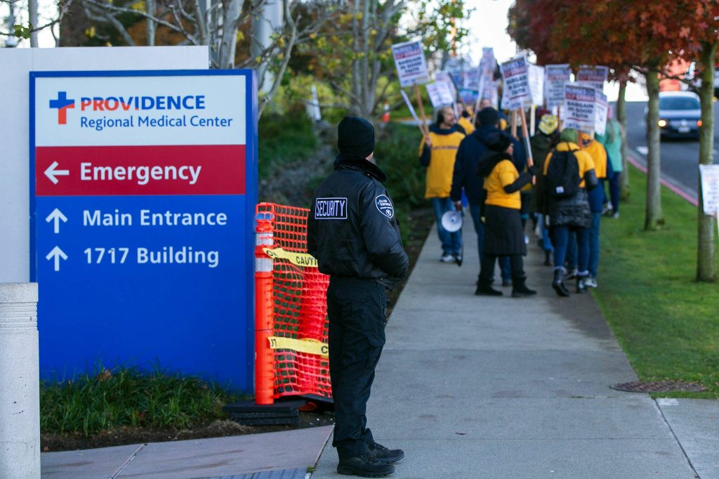 A security guard stands near the ER entrance as Providence nurses picket in front of the hospital during the first day of their planned five-day strike Tuesday, Nov. 14, 2023, at Providence Regional Medical Center in Everett, Washington. (Ryan Berry / The Herald)