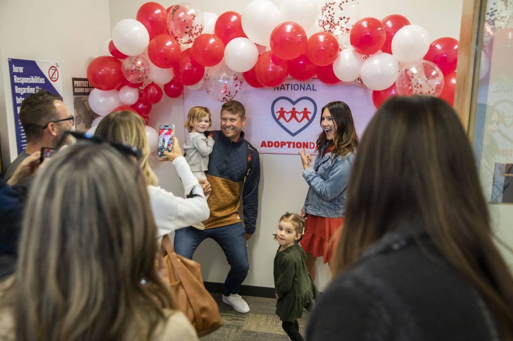 Families pause to take photos with a National Adoption Day sign on Friday, Nov. 17, 2023 in Everett, Washington. (Olivia Vanni / The Herald)