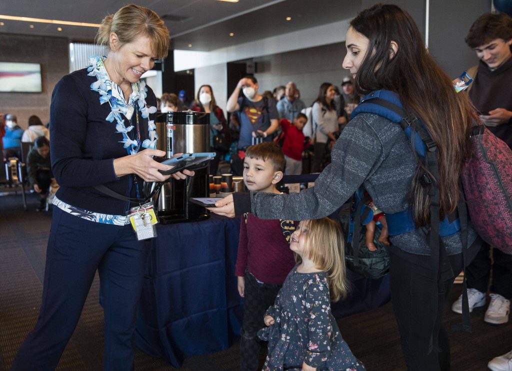 Katie Wallace, left, checks people into the first flight from Paine Field to Honolulu on Friday, Nov. 17, 2023 in Everett, Washington. (Olivia Vanni / The Herald)