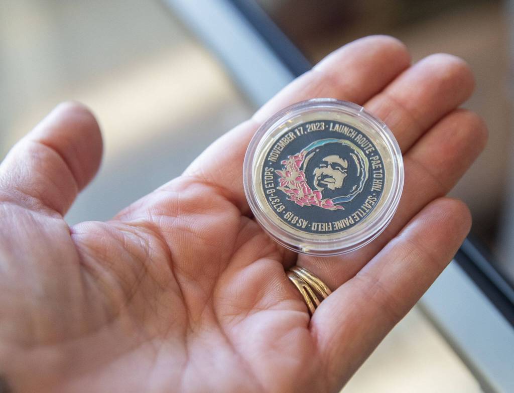 Coins commemorating the first flight from Paine Field to Honolulu are handed out to passengers on Friday, Nov. 17, 2023 in Everett, Washington. (Olivia Vanni / The Herald)