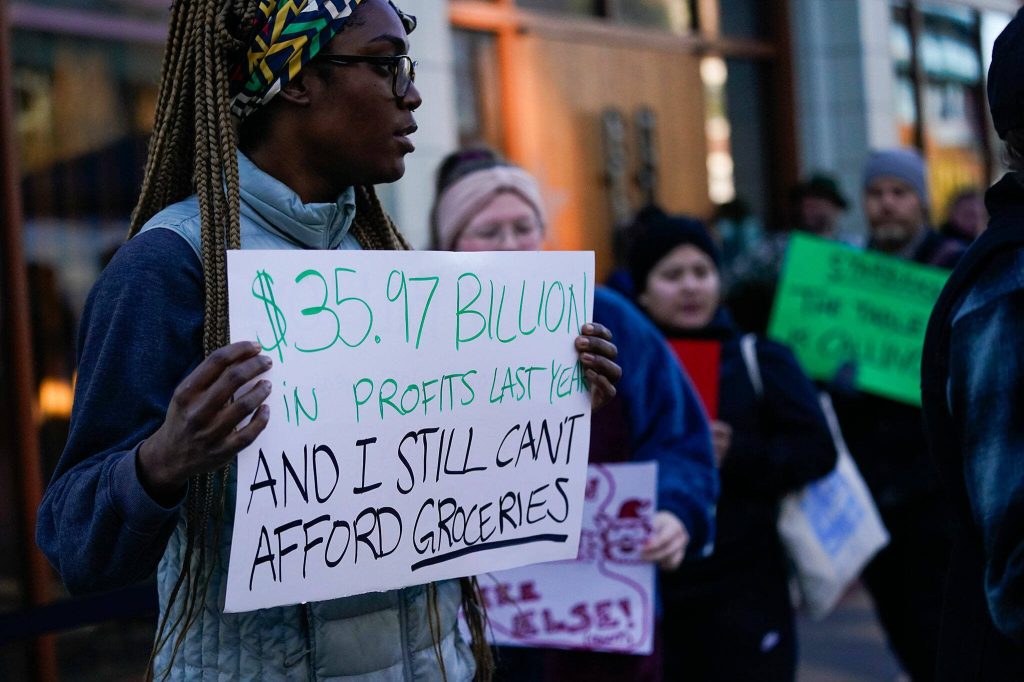 A demonstrator holds up a sign referencing Starbucks profits as workers participate in a walkout and strike organized by Starbucks Workers United during the companys Red Cup Day Thursday, Nov. 16, 2023, at the companys first Reserve roastery in Seattle. (AP Photo/Lindsey Wasson)