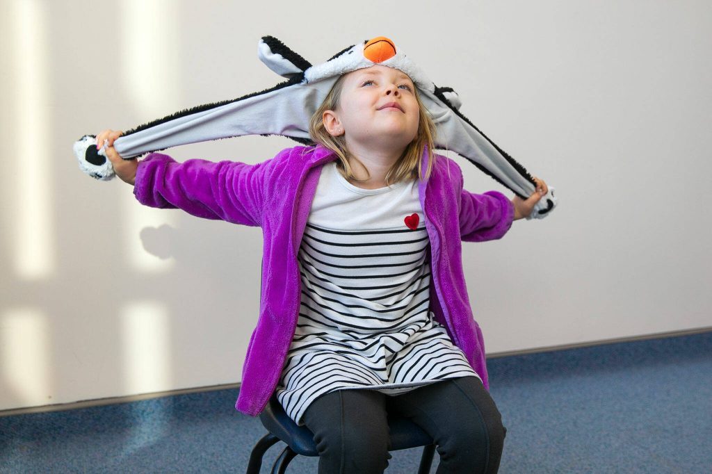 Charley plays with her penguin hat as she answers questions during an interview with the Herald on Monday, Nov. 20, 2023, at Jackson Elementary School in Everett, Washington. Charley does not own a turkey hat. (Ryan Berry / The Herald)