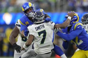 Seattle Seahawks quarterback Geno Smith (7) is injured while being tackled by Los Angeles Rams defensive tackle Aaron Donald, left, and linebacker Ochaun Mathis, right, during the second half of Sundays game in Inglewood, Calif. (AP Photo/Mark J. Terrill)
