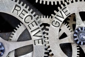 Macro photo of tooth wheel mechanism with imprinted RECEIVE, GIVE concept words