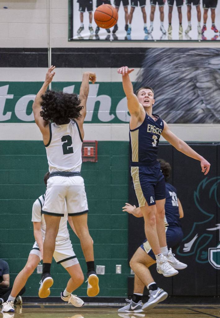 Arlingtons Jackson Trotter leaps in the air to try and block a shot by Jacksons Seamus Williams during the game on Tuesday, Nov. 28, 2023 in Everett, Washington. (Olivia Vanni / The Herald)