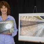 Catherine Bassetti poses for a photo with her book “Building Seattle's State Route 99 Supertunnel: Journey from Light to Light” in her home studio in Shoreline, Washington on Friday, May 19, 2023. (Annie Barker / The Herald)