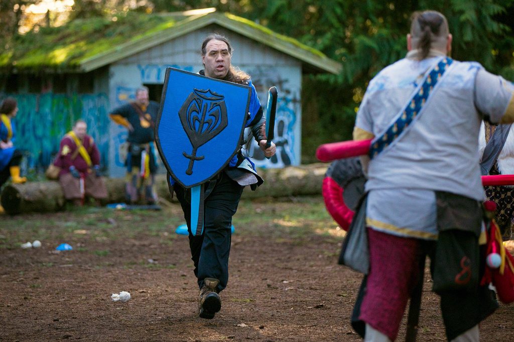 Paul Campbell, persona Aidan, charges forward while wielding a homemade shield during a weekly meeting of the Amtgard LARPing group The Hollow on Jan. 29, at McCollum Park. (Ryan Berry / The Herald)