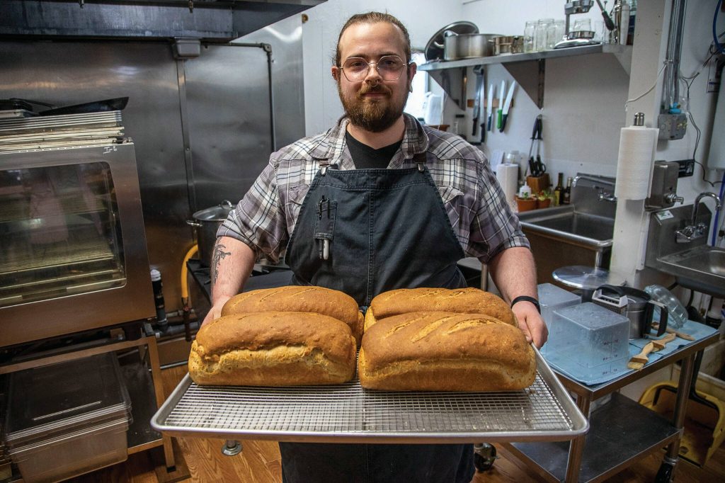 Danny Volz holds a pan of freshly baked bread at Dolce Bakery and Cafe in Greenbank. (Annie Barker / The Herald)