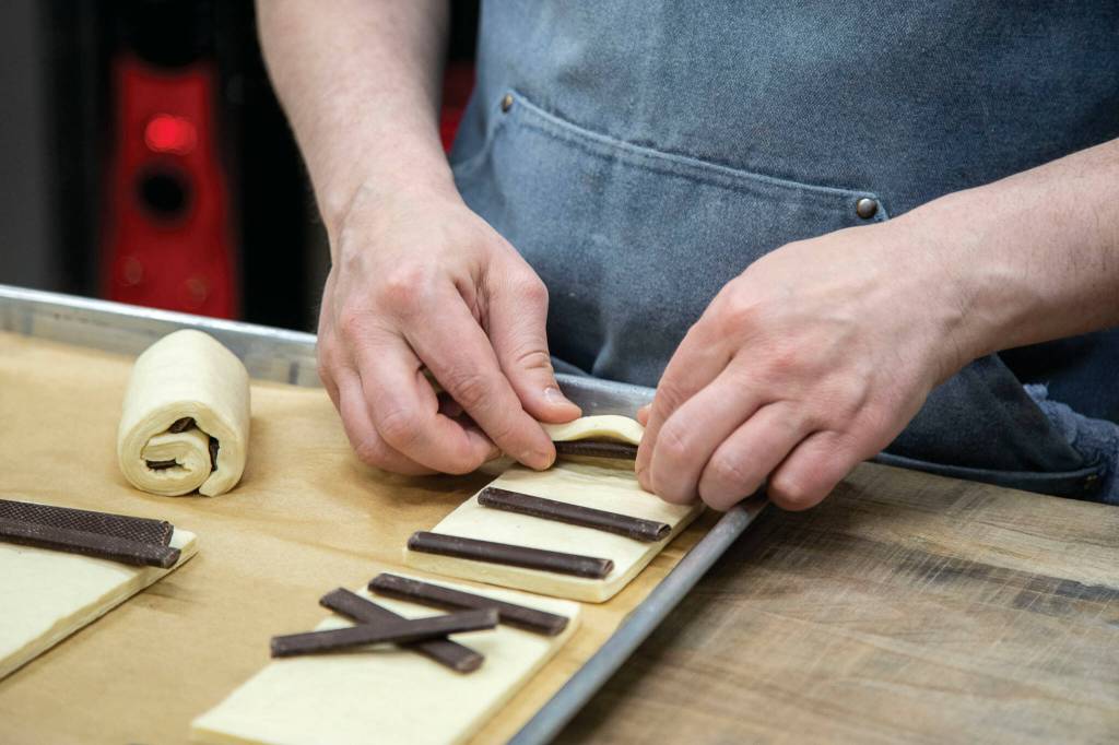 Pastry baker Jonathan Hart prepares chocolate croissants at Seabiscuit Bakery. (Annie Barker / The Herald)