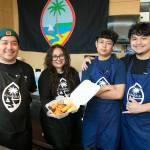 Guam Grub owner and head chef Julita Atoigue-Javier, center left, stands behind the counter with her brother-in-law Angelo Javier, left, and sons Timothy, 13, and John, 21, right, at the Everett Mall. (Ryan Berry / The Herald)
