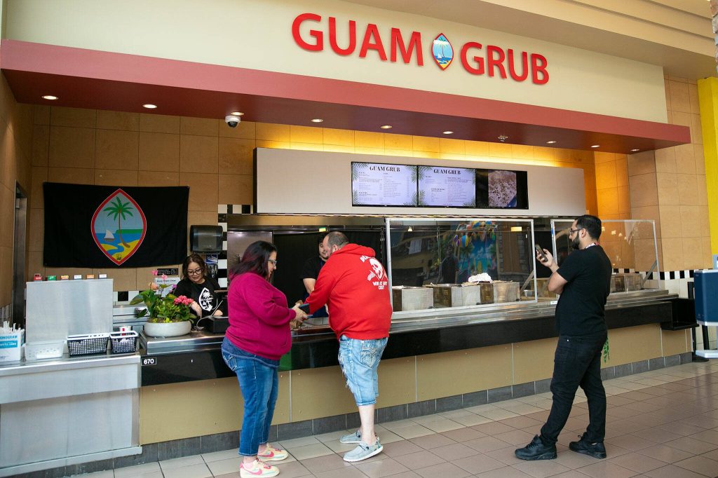 Customers pick up orders at Guam Grub at the Everett Mall in Everett, Washington. Owner Julita Atoigue-Javier said her business has been selling out almost every day since opening. (Ryan Berry / The Herald)