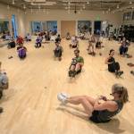 Instructor Gael Gebow shows her class how to do Russian twists during her Boot Camp fitness class Monday, Nov. 13, 2023, at the YMCA in Everett, Washington. (Ryan Berry / The Herald)