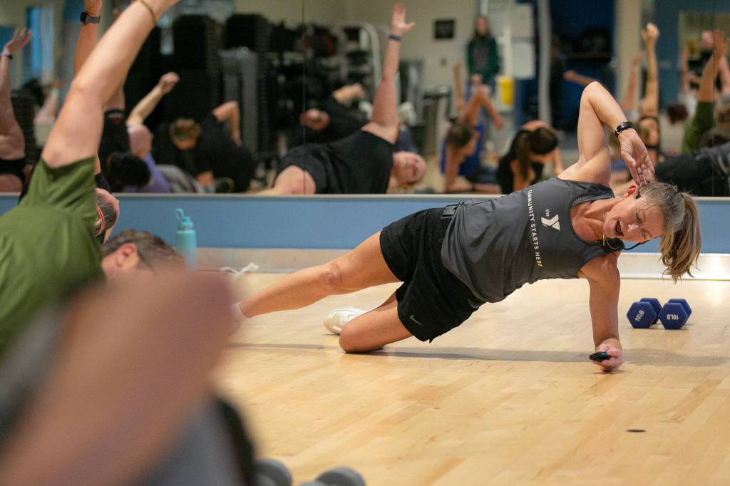 Instructor Gael Gebow checks her stopwatch while tracking her groups exercises during her Boot Camp fitness class Monday, Nov. 13, 2023, at the YMCA in Everett, Washington. (Ryan Berry / The Herald)