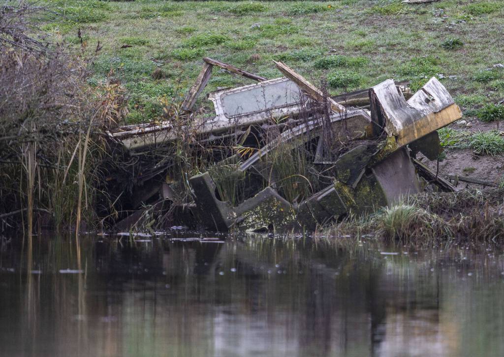 Remnants of a boat are visible along the riverbank of Union Slough on Tuesday, Nov. 21, 2023 in Everett, Washington. (Olivia Vanni / The Herald)