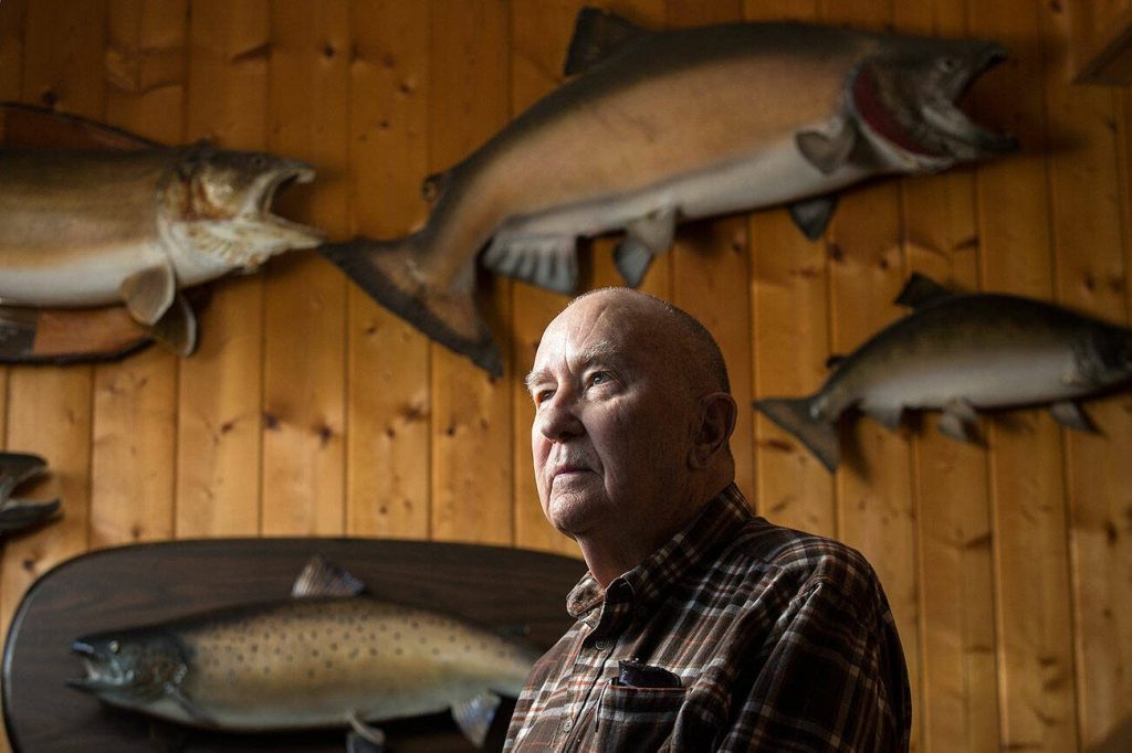 Wayne Kruse stands with fishing trophies at his home on Lake Cavanaugh on Tuesday, March 6, 2018 in Mount Vernon, Washington. (Andy Bronson / The Herald)