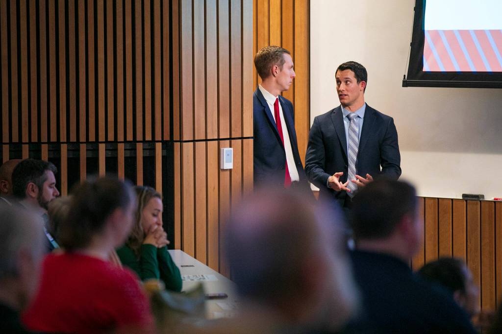 Snohomish County Councilmembers Nate Nehring and Jared Mead wait in the wings and chat during their Building Bridges Summit on Monday, Dec. 4, 2023, at Washington State University Everett in Everett, Washington. (Ryan Berry / The Herald)