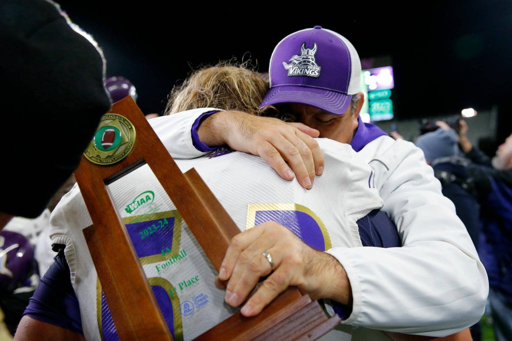 Lake Stevens head coach Tom Tri hugs senior Bryce Slezak after winning against Graham-Kapowsin in the WIAA 4A Football State Championship on Saturday, Dec. 2, 2023, at Husky Stadium in Seattle, Washington. (Ryan Berry / The Herald)