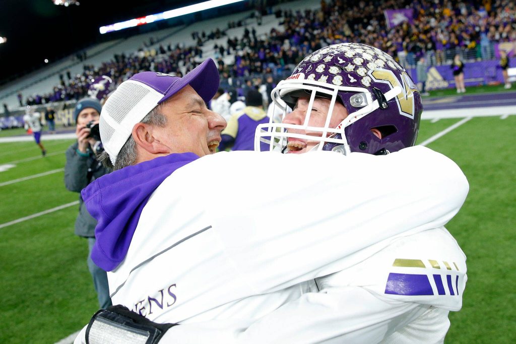 Lake Stevens head coach Tom Tri hugs quarterback Kolton Matson after the Vikings victory against Graham-Kapowsin in the WIAA 4A Football State Championship on Saturday, Dec. 2, 2023, at Husky Stadium in Seattle, Washington. (Ryan Berry / The Herald)