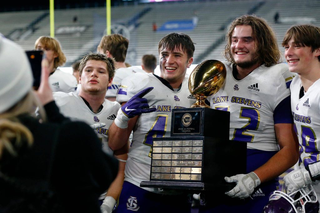 Lake Stevens players take photos with the championship trophy after their win over Graham-Kapowsin during the WIAA 4A Football State Championship on Saturday, Dec. 2, 2023, at Husky Stadium in Seattle, Washington. (Ryan Berry / The Herald)