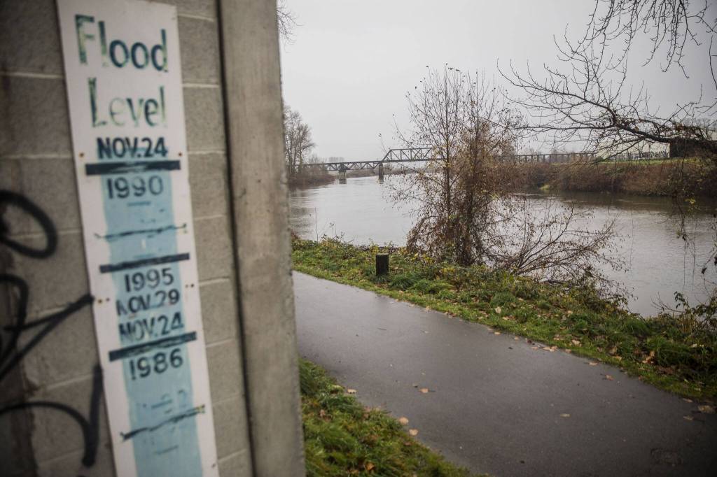 A sign showing the river levels of previous floods is visible along the Snohomish River on Monday, Dec. 4, 2023 in Snohomish, Washington. (Olivia Vanni / The Herald)