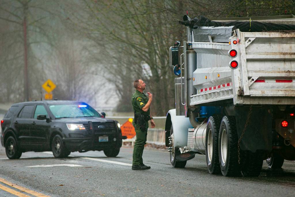 A Snohomish County deputy blocks off Highway 530 at Twin Rivers Park and begins turning drivers back towards Arlington during heavy flooding on Tuesday, Dec. 5, 2023, in Arlington, Washington. (Ryan Berry / The Herald)