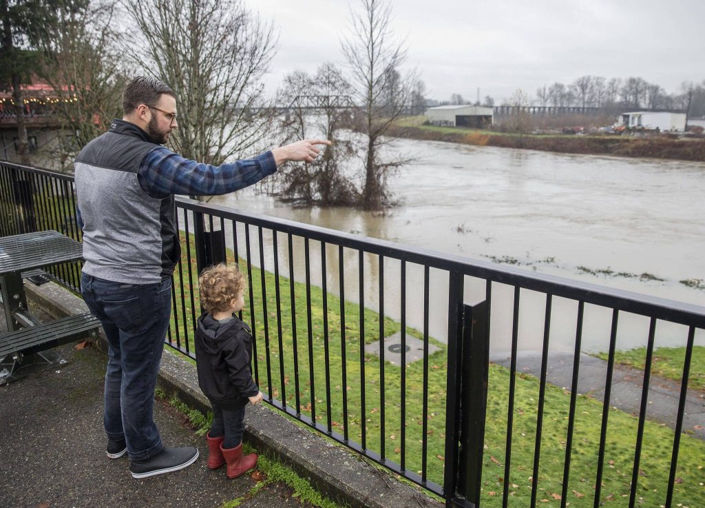 Spencer Lane, left, talks to his son Roland Lane, 2, and points out where they were walking on the Snohomish Riverfront Trail the night before when the trail was not flooded on Wednesday, Dec. 6, 2023 in Snohomish, Washington. (Olivia Vanni / The Herald)