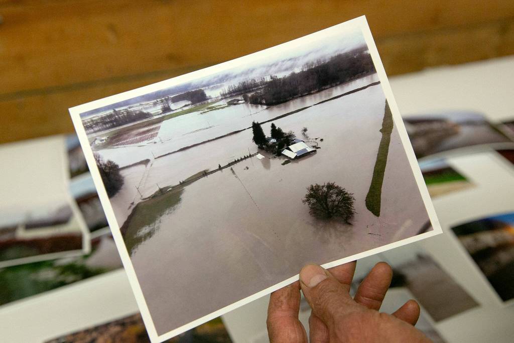 Spencer Fuentes, of Hazel Blue Acres, holds a photo given to him of the flooding near his property on Thursday, Dec. 7, 2023, in Silvana, Washington. (Ryan Berry / The Herald)