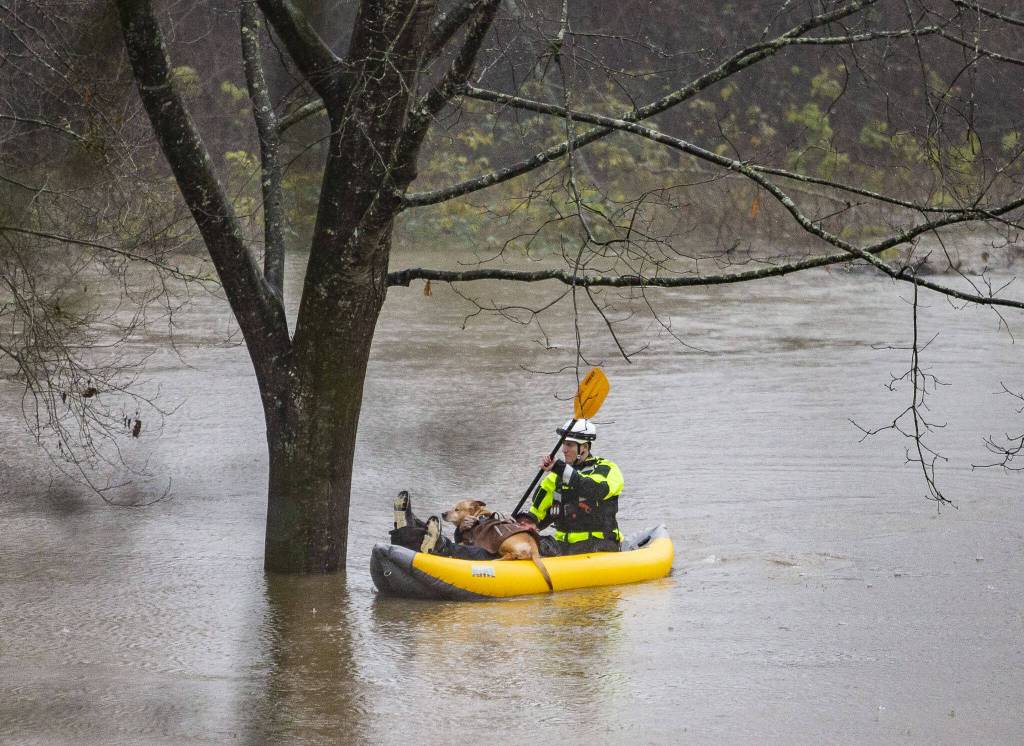Snohomish Regional Fire & Rescue paddle in to shore with a man and his dog from a portion of Al Borlin Park where they were stranded with three other people on Tuesday, Dec. 5, 2023 in Monroe, Washington. (Olivia Vanni / The Herald)