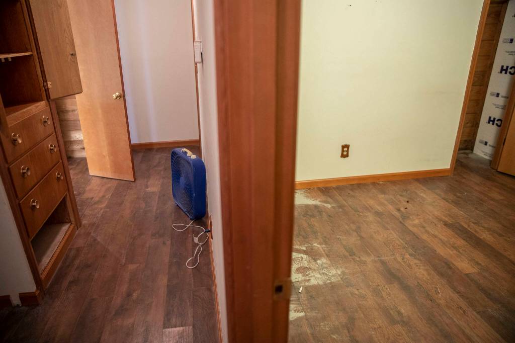 River silt cover parts of the floor and fans blow air to prevent mold inside the home of Dannika Prime and Colyn Baldwin on Tuesday, Dec. 12, 2023 in Silvana, Washington. (Olivia Vanni / The Herald)