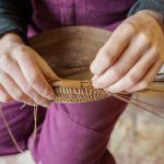 Mackensie Bennett weaves together pine needles to create a basket, a process which takes several hours. (Photo by David Welton)