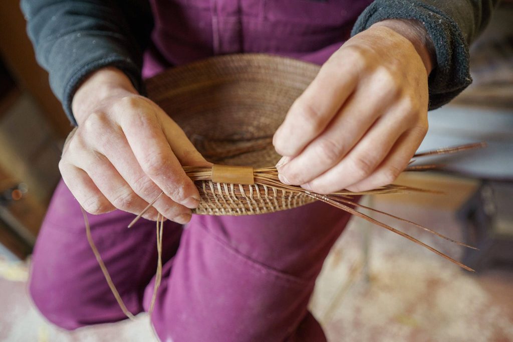 Mackensie Bennett weaves together pine needles to create a basket, a process which takes several hours. (Photo by David Welton)