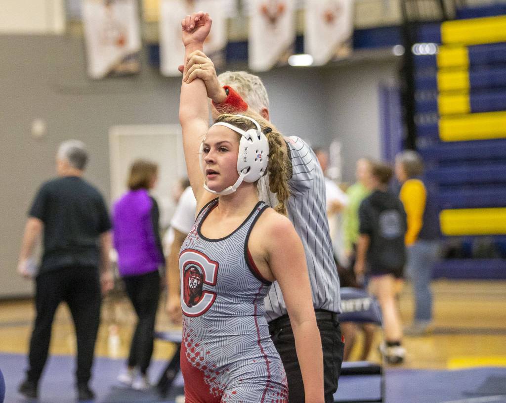 A Cascade wrestler has her arm raised after beat her opponent on Wednesday, Dec. 13, 2023 in Everett, Washington. (Olivia Vanni / The Herald)