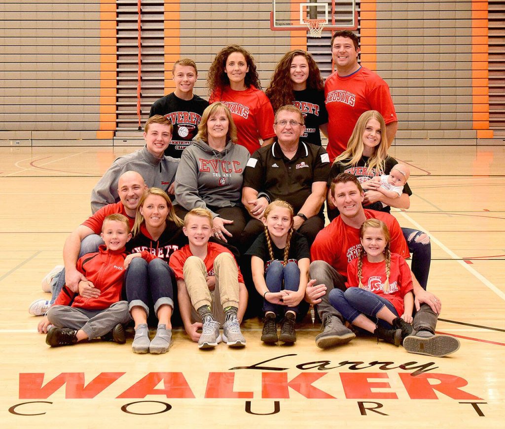 Former Everett Community College basketball coach Larry Walker (middle row, second to right) poses with his family, including grandson and current Trojans mens basketball player Ethan Martin (middle row, left) on the court that bears his name. (Everett Community College photo)