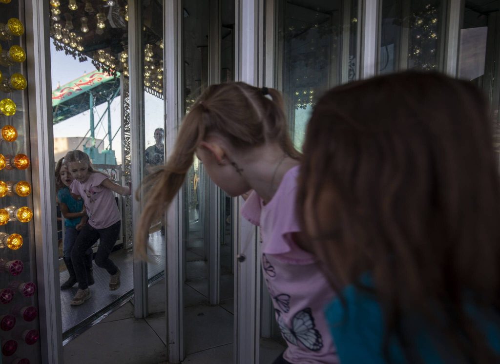 Children enter a house of mirrors during the Kla Ha Ya Days carnival at Harvey Field on Thursday, July 13, 2023, in Snohomish, Washington. (Annie Barker / The Herald)