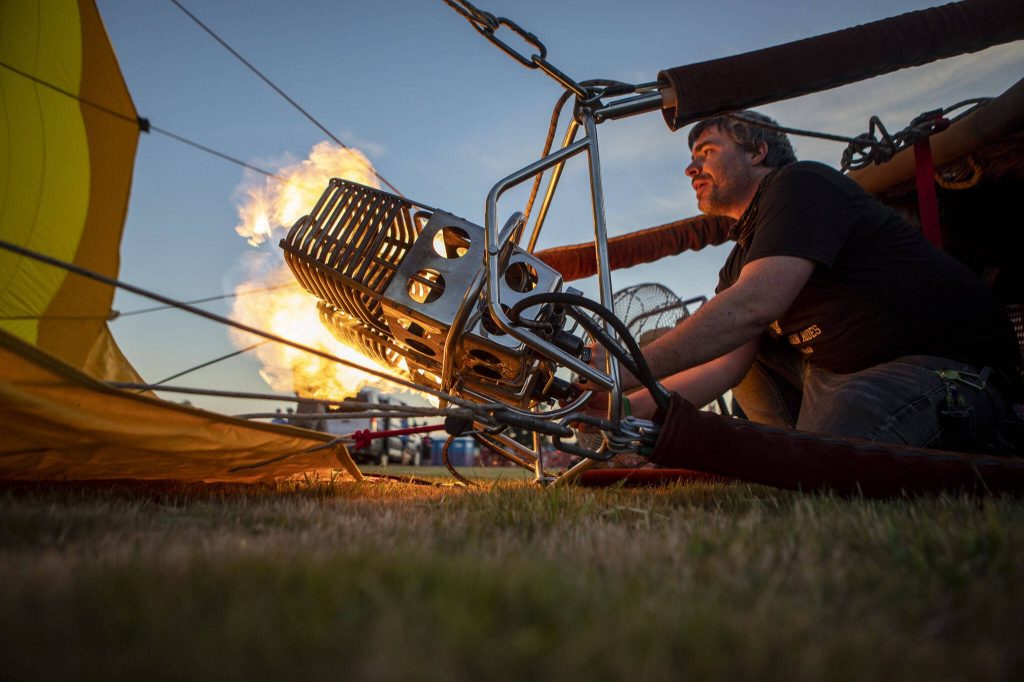 Erin Romaneschi, 33, fires up the burner and injects a hot air balloon with flames to heat the air inside during Kla Ha Ya Days at Harvey Field on Friday, July 14, 2023, in Snohomish, Washington. (Annie Barker / The Herald)