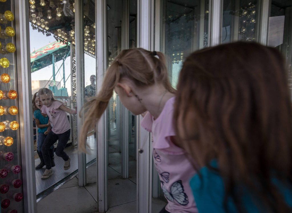 Children enter a house of mirrors during the Kla Ha Ya Days carnival at Harvey Field on Thursday, July 13, 2023, in Snohomish, Washington. (Annie Barker / The Herald)